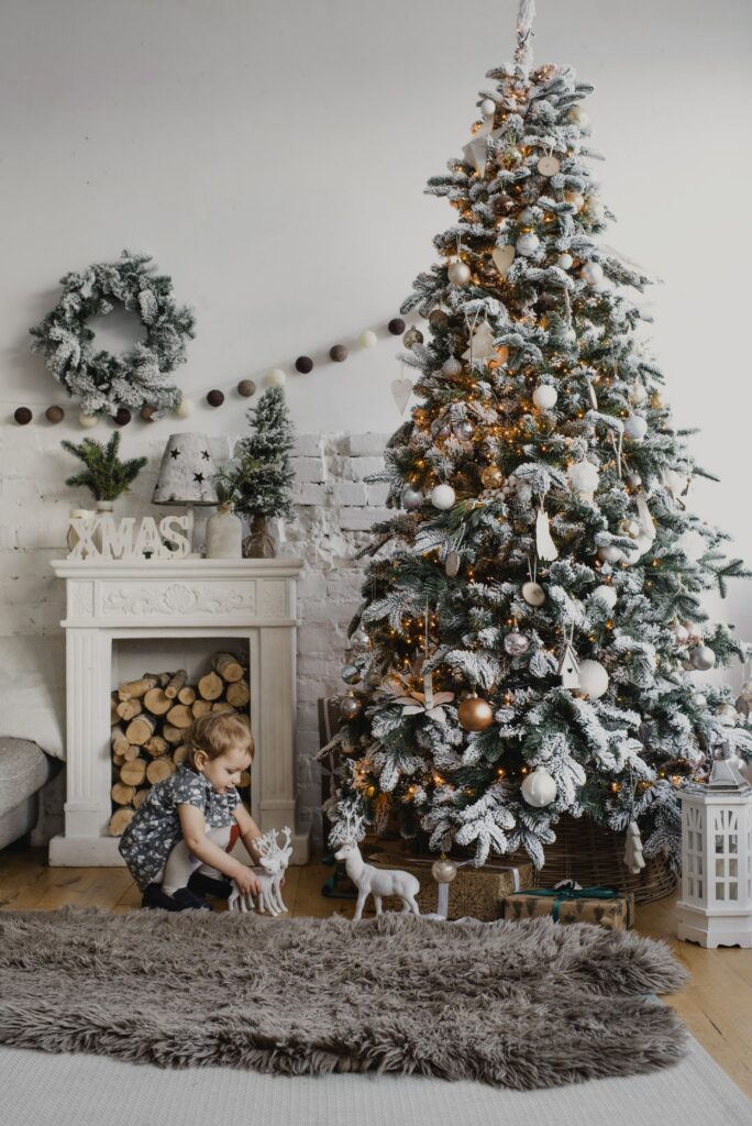 A young child playing on the floor near a decorated Christmas tree